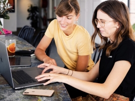 Two women discussing while looking at a laptop.